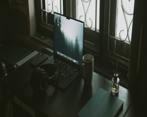 A laptop on a desk showing remote work setup by a window