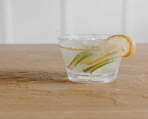 A glass of fresh water and slices of tropical fruit on a wooden table